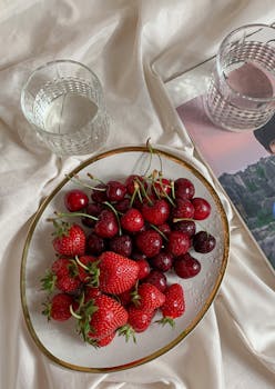 Delicious strawberries and cherries on a stylish plate with a serene background, perfect for healthy lifestyle imagery.