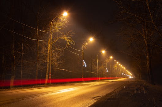 A scenic night road with blurred car light trails captured in long exposure, creating a dynamic urban scene.