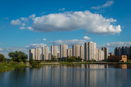Free Tall apartment buildings reflecting on a serene lake under a clear blue sky, showcasing urban beauty. Stock Photo
