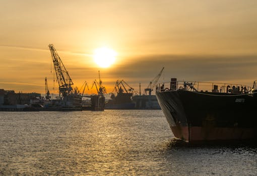 Cargo ships docked at an industrial port during a stunning sunset, emphasizing maritime transportation.