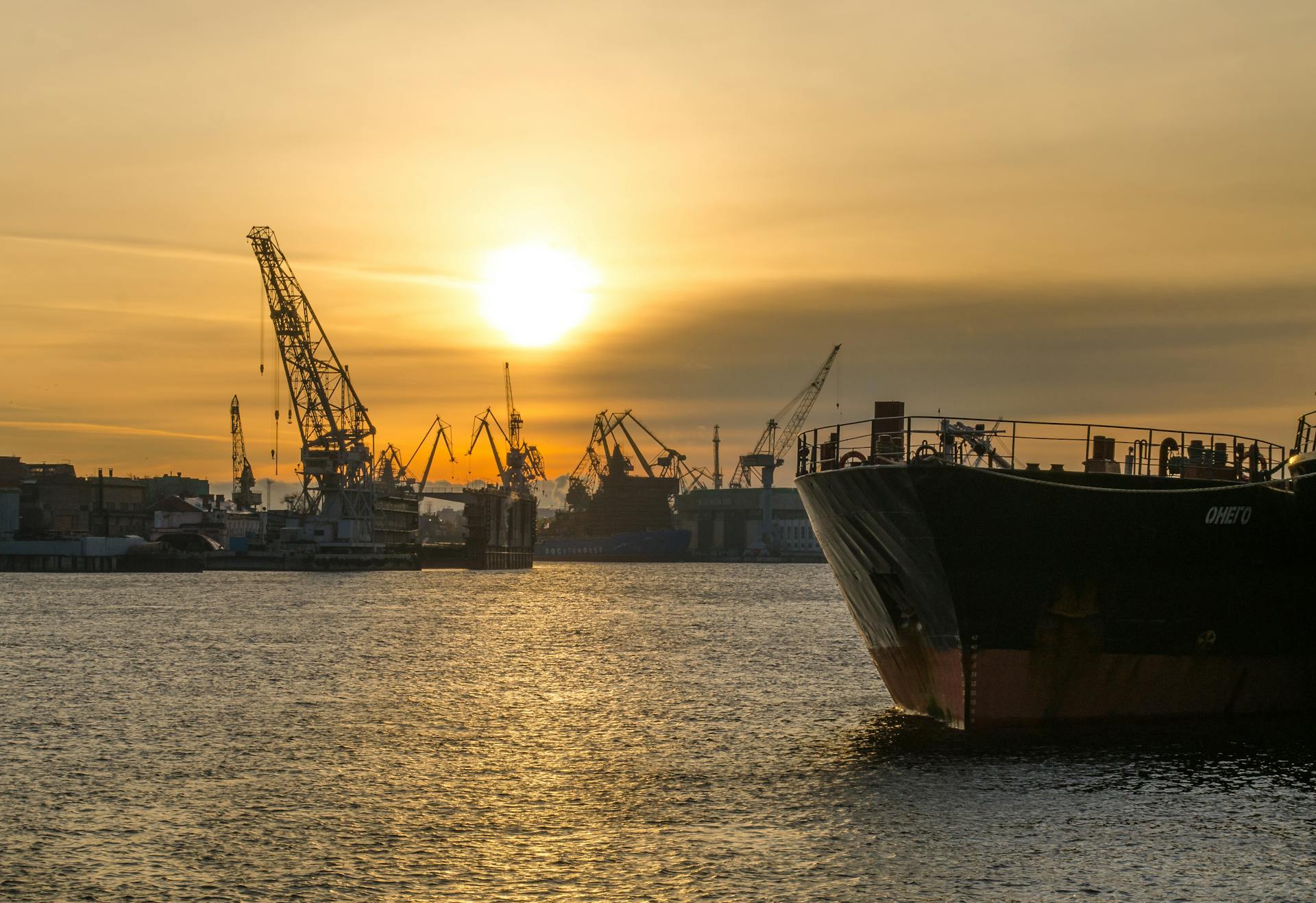 Cargo ships docked at an industrial port during a stunning sunset, emphasizing maritime transportation.