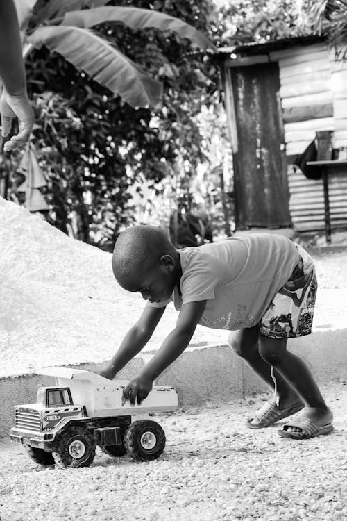 Black and White Photo of a Kid Playing with a Toy