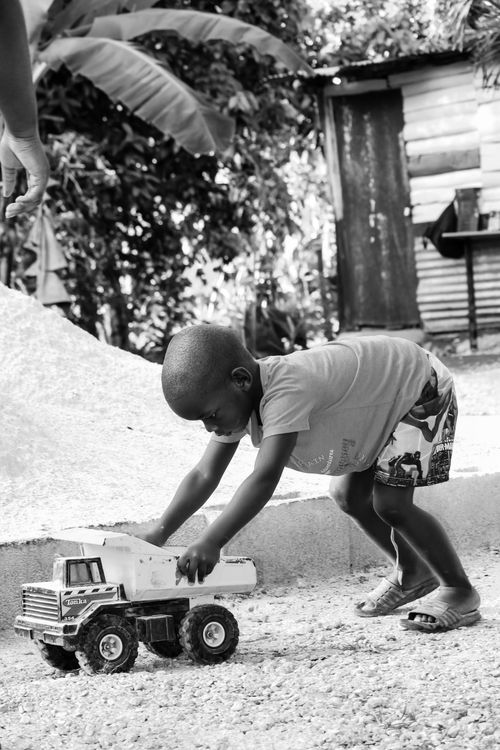 Free Black and white photo of a young boy playing with a toy truck outdoors, capturing childhood innocence. Stock Photo