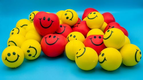 Free A collection of vibrant yellow and red smiley stress balls arranged on a blue surface. Stock Photo