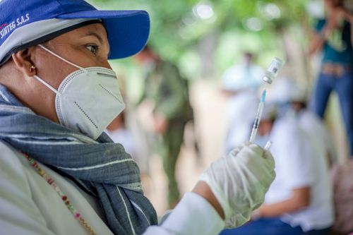 Free A healthcare worker prepares a vaccine outdoors in Ovejas, Colombia, emphasizing COVID-19 safety and healthcare provision. Stock Photo