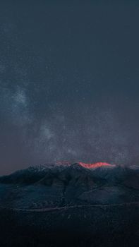 A breathtaking view of a starry night sky illuminating a serene mountain range.