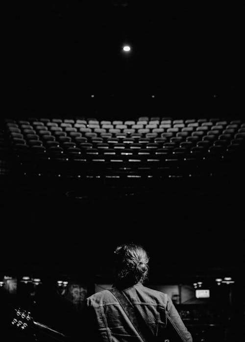 Grayscale Photo of a Musician inside an Empty Theater