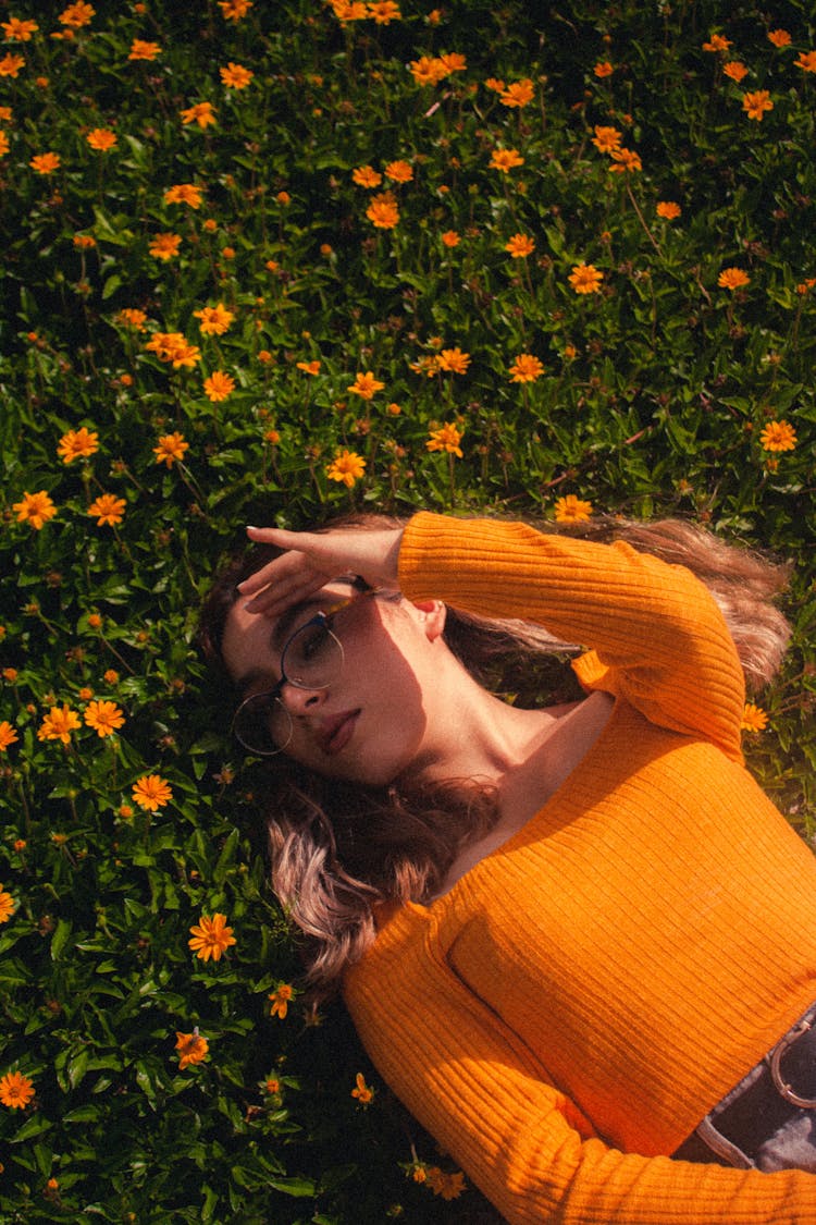 A Woman In Yellow Ribbed Long Sleeve Shirt Lying On Yellow Flower Field