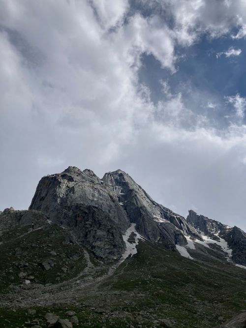 Free A majestic rocky mountain peak with patches of snow under a cloudy sky, showcasing nature's beauty. Stock Photo