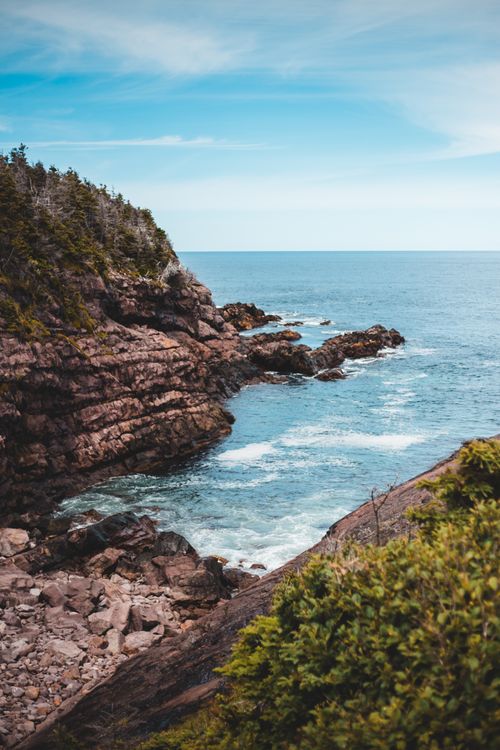 Free Breathtaking view of rocky cliffs meeting the vast ocean under a clear blue sky. Stock Photo