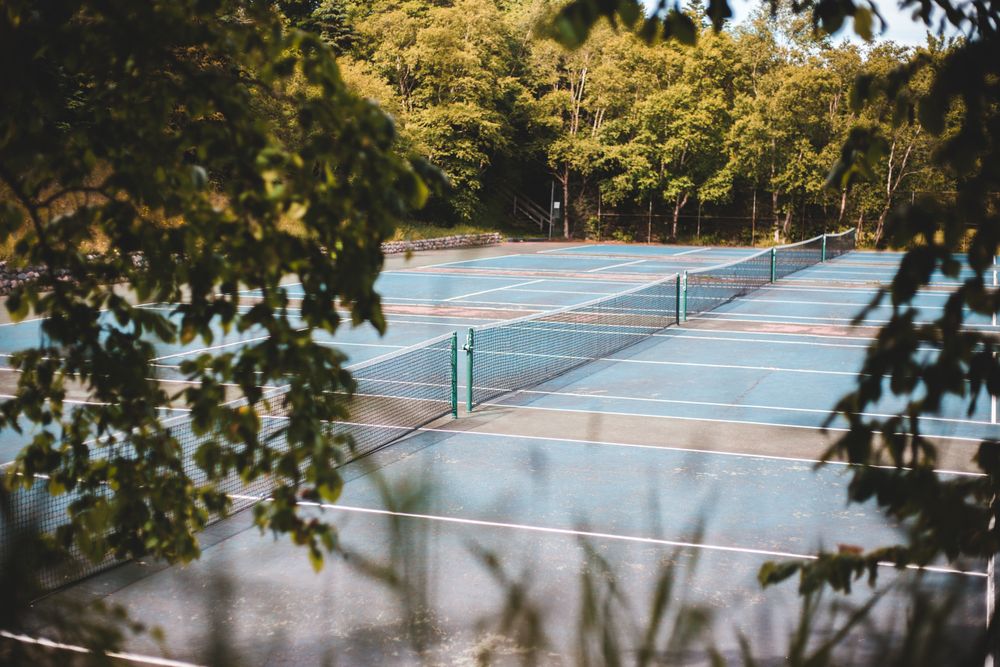 Outdoor blue tennis courts surrounded by trees