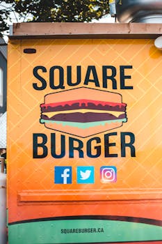Vibrant Square Burger food truck sign with social media icons displayed outdoors.