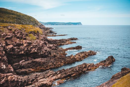 Stunning view of Cape Spear's rugged cliffs meeting the Atlantic Ocean on a clear summer day.