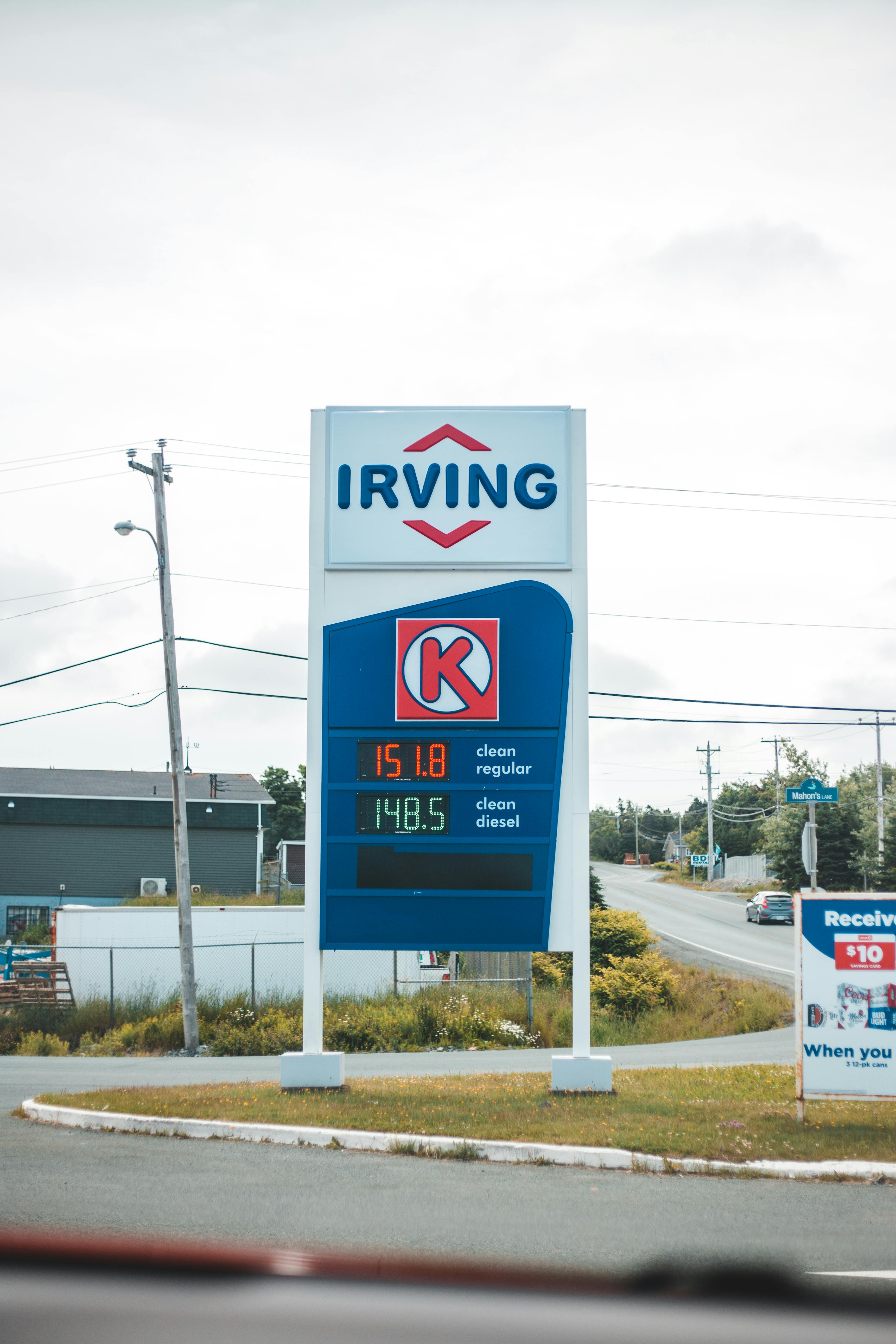 a gas station signage with prices erected on grass near the road