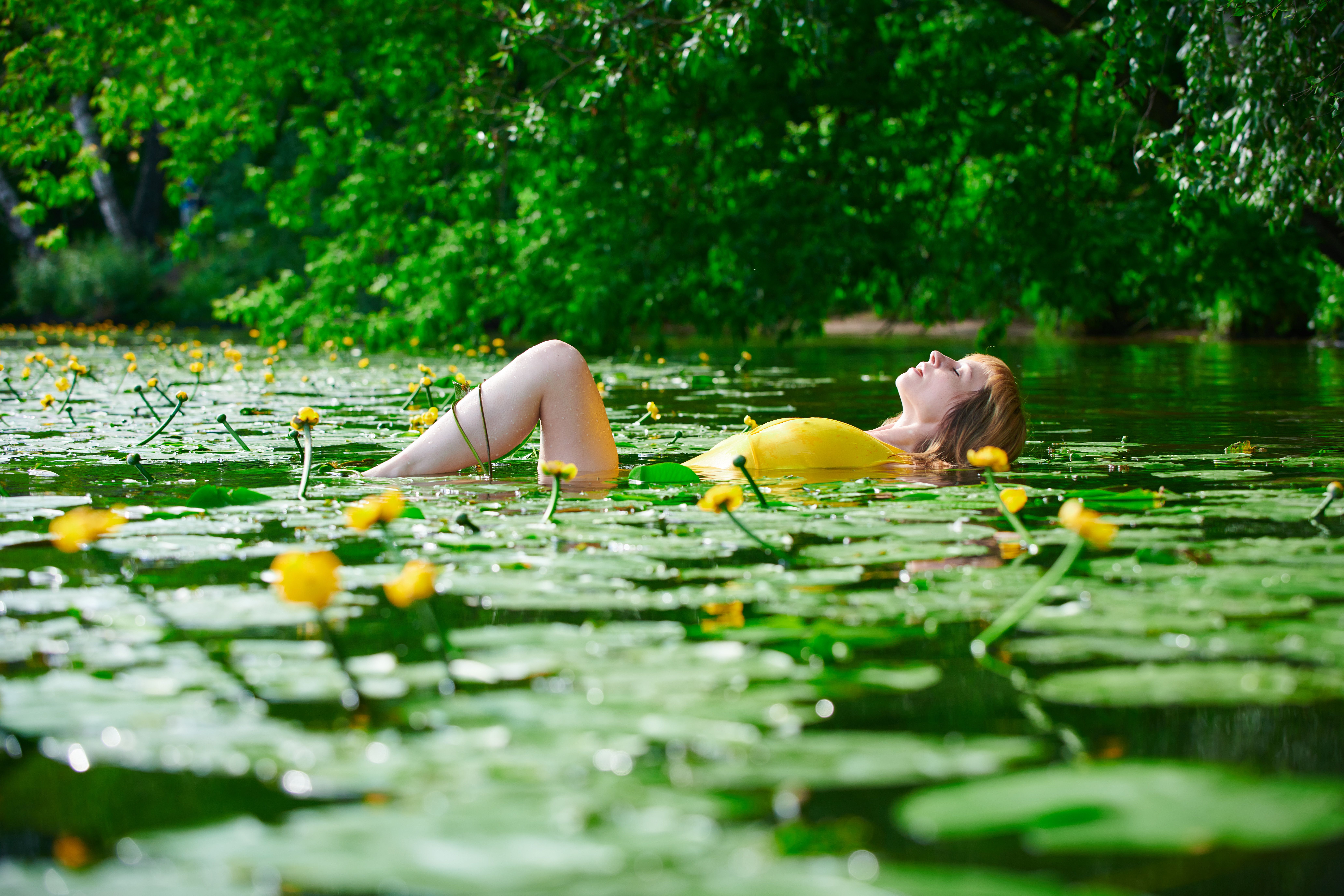 A serene moment of a woman floating among vibrant water lilies in a tranquil lake.