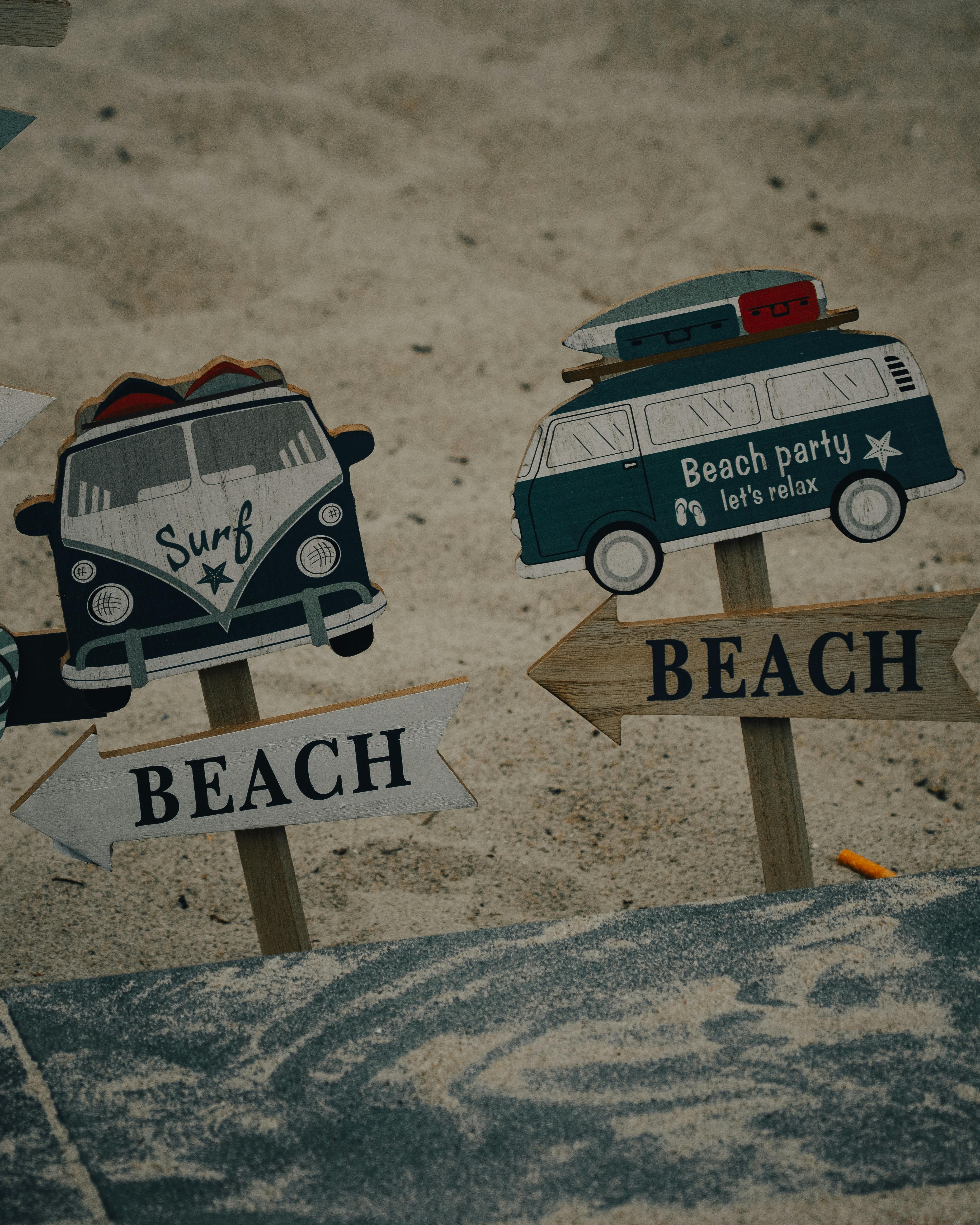 Beach-themed signposts with camper designs in sand, perfect for summer vibes