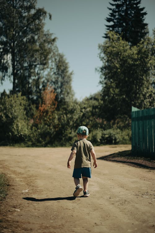A Little Boy Walking Alone on Dirt Road