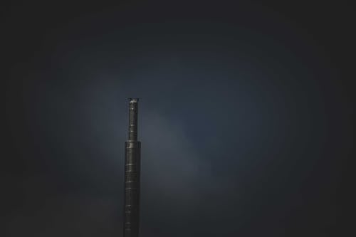 A Stainless Steel Industrial Chimney Emitting Smoke on Dark Sky