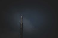 A Stainless Steel Industrial Chimney Emitting Smoke on Dark Sky