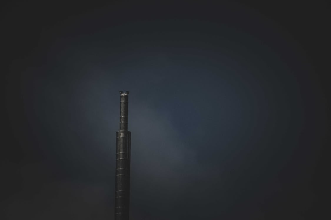 Free A Stainless Steel Industrial Chimney Emitting Smoke on Dark Sky Stock Photo
