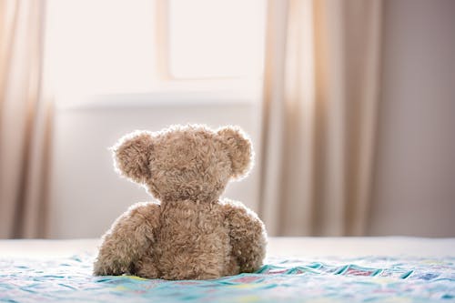 Плюшевая игрушка бурый медведь на кровати
