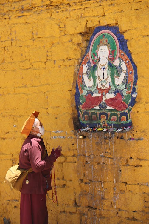 Person Praying in Front of a Buddha Painting