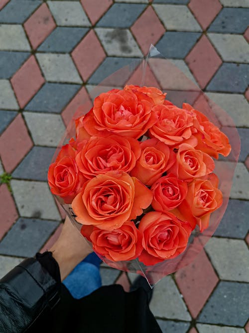Close-Up Shot of a Person Holding a Bouquet of Orange Roses