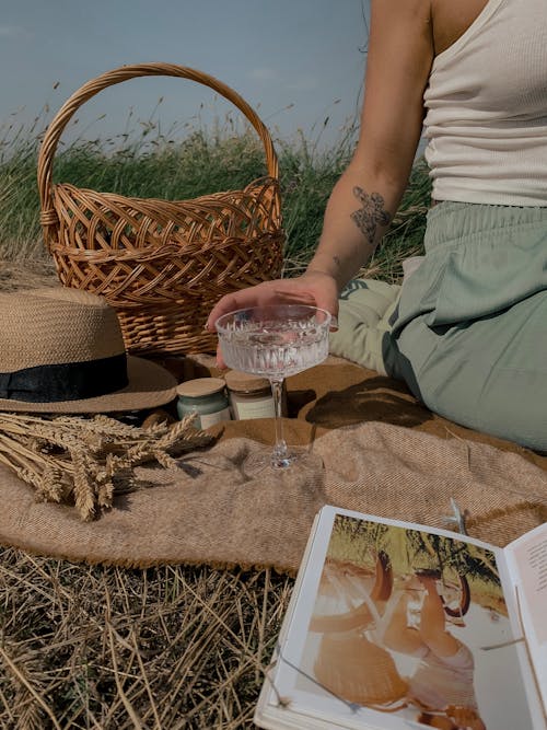 Person Holding Wine Glass while Having a Picnic Outdoors