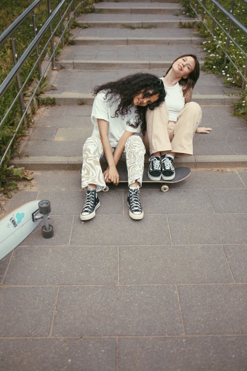 Free Two young women sitting on skateboards outdoors on a stairway, enjoying a relaxed moment. Stock Photo