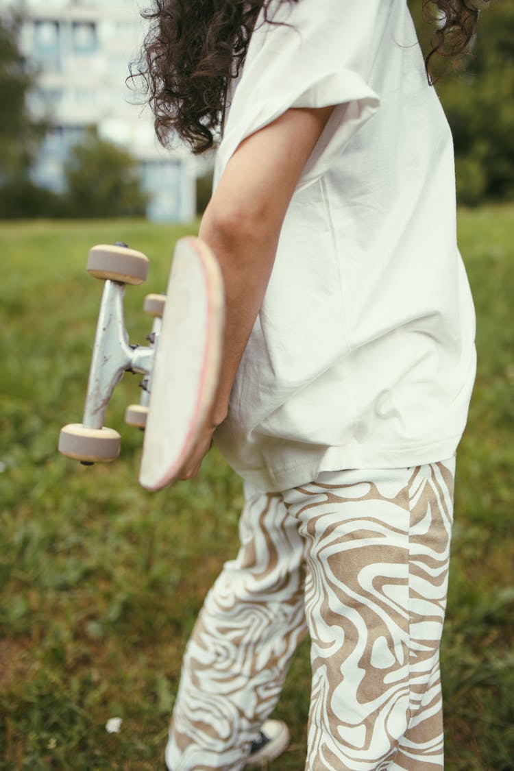 Person Holding A Skateboard At The Back