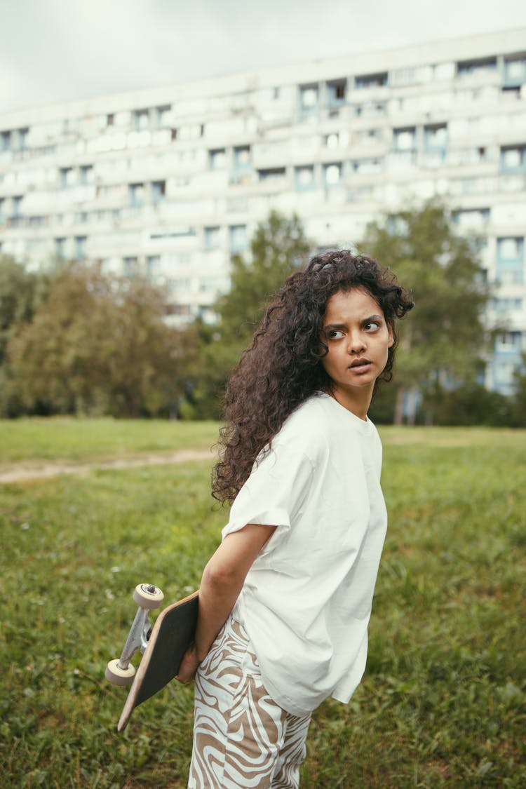 Woman Holding A Skateboard At Her Back