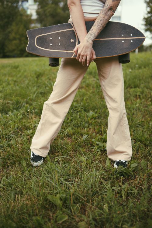Free A skater with tattoos holding a longboard in an outdoor park setting. Stock Photo