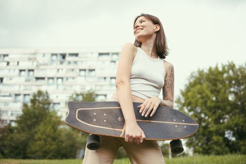 Free Smiling woman holding skateboard outdoors, showcasing urban lifestyle. Stock Photo