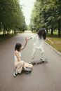 2 Women in White Long Sleeve Shirt and White Pants Sitting on Gray Concrete Road during