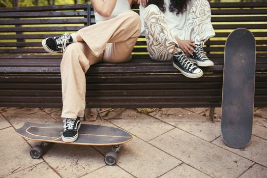 Person in Brown Pants and Black and White Sneakers Sitting on Brown Wooden Bench