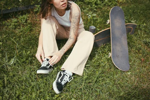 Female Skater Tying her Shoes while Sitting on the Grass