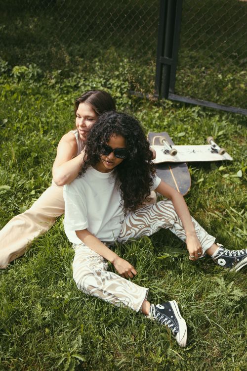 Free Two women enjoying leisure time on grass with a skateboard outdoors. Stock Photo