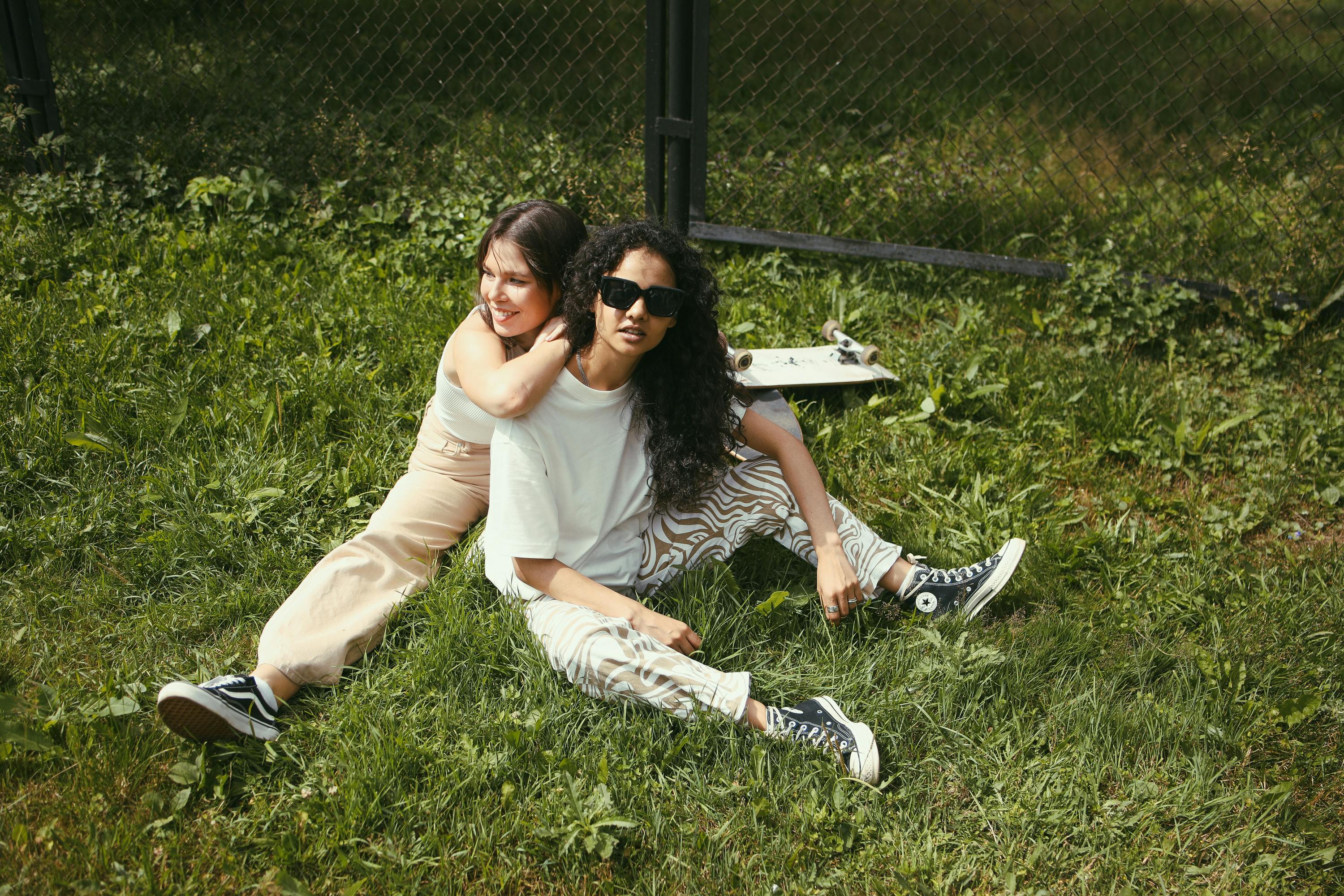 two women sitting on green grass