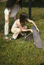 Woman in White Tank Top and White Pants Sitting on Green Grass Field