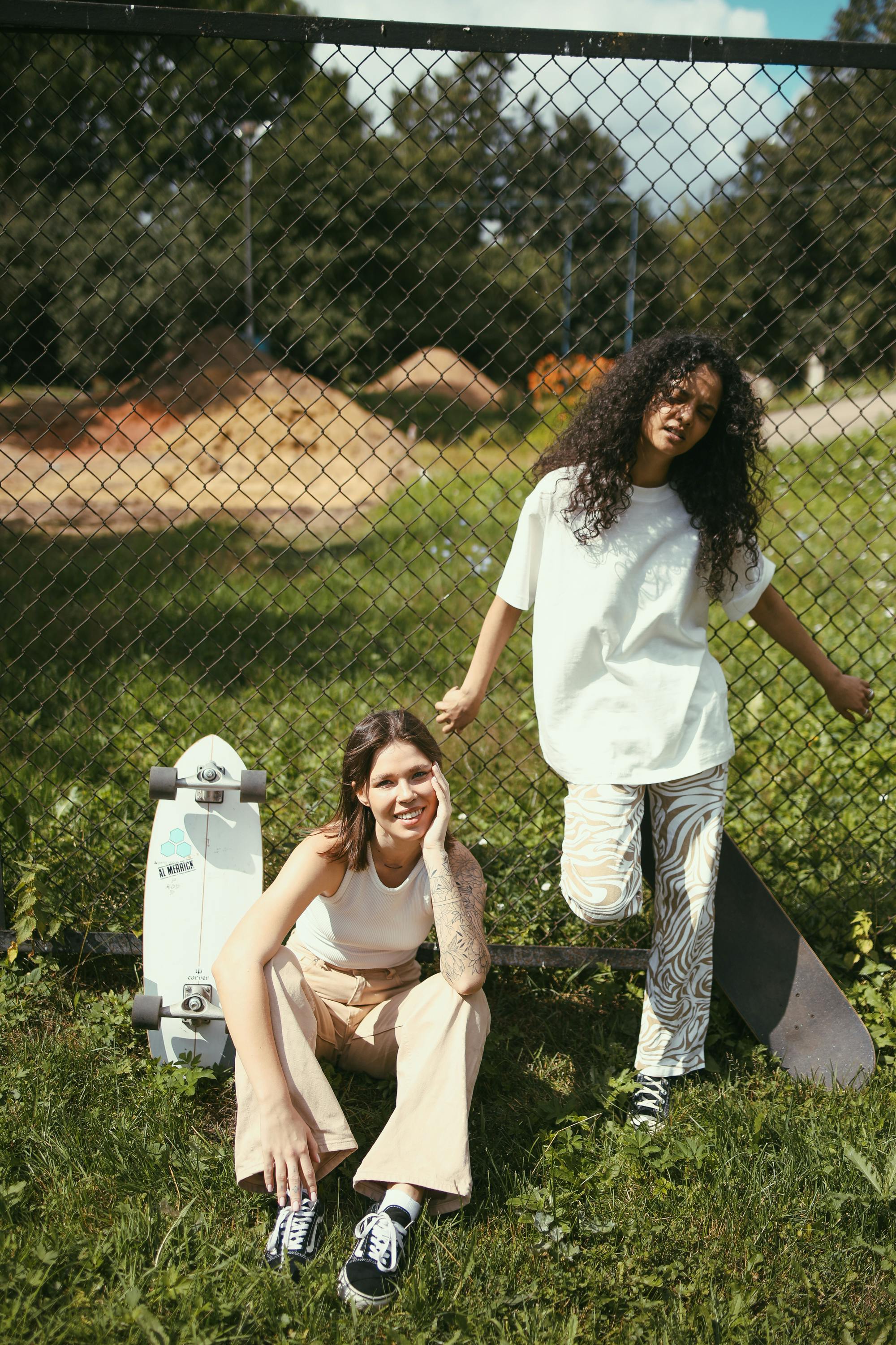 women in white top and pants near a metal fence