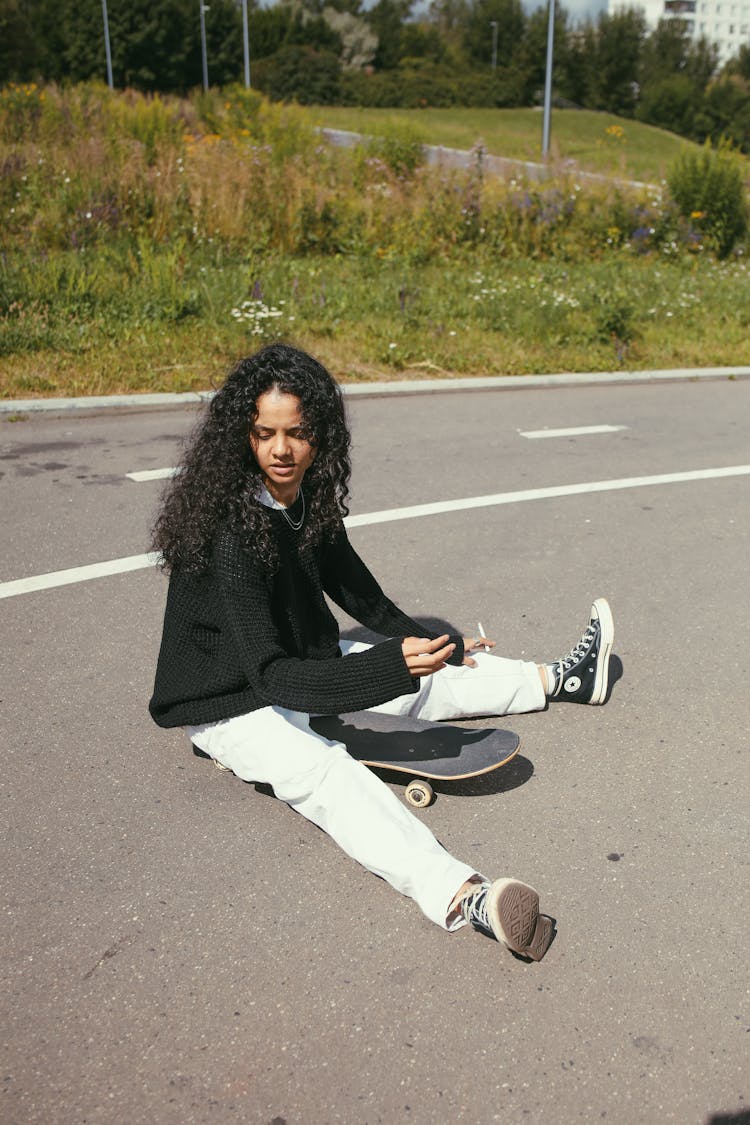 Woman In Black Top Sitting On Skateboard