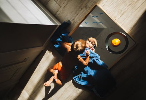 A child creatively drawing on a mirror at home, viewed from above.
