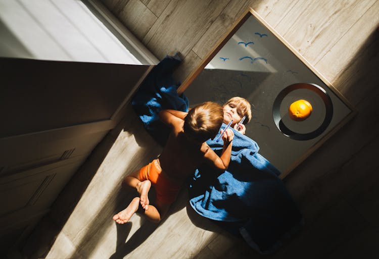 Boy Lying On Floor Drawing On Mirror