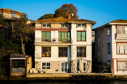 Free A charming old waterfront house with a rustic and shabby appearance, featuring large glass windows and a wooden facade. Stock Photo