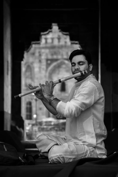 Free A man in traditional attire playing the flute with closed eyes in a serene setting. Stock Photo