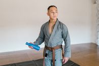 Man in Gray Kimono and Brown Belt Holding Blue Tumbler