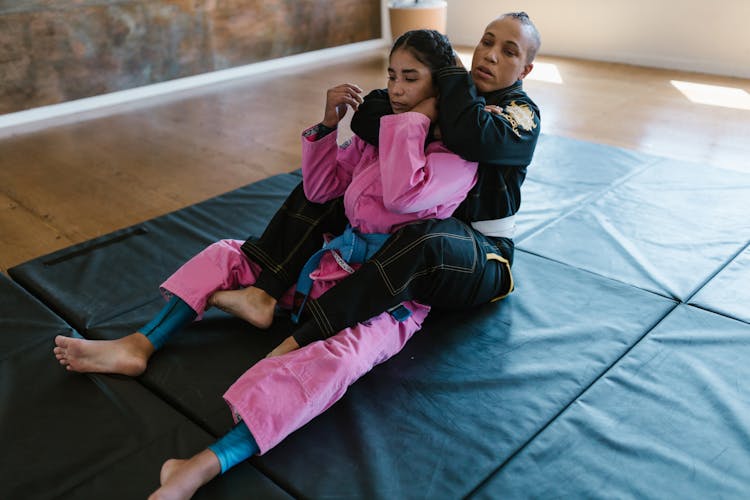 Women In Taekwondo Uniforms Sparring On The Mat