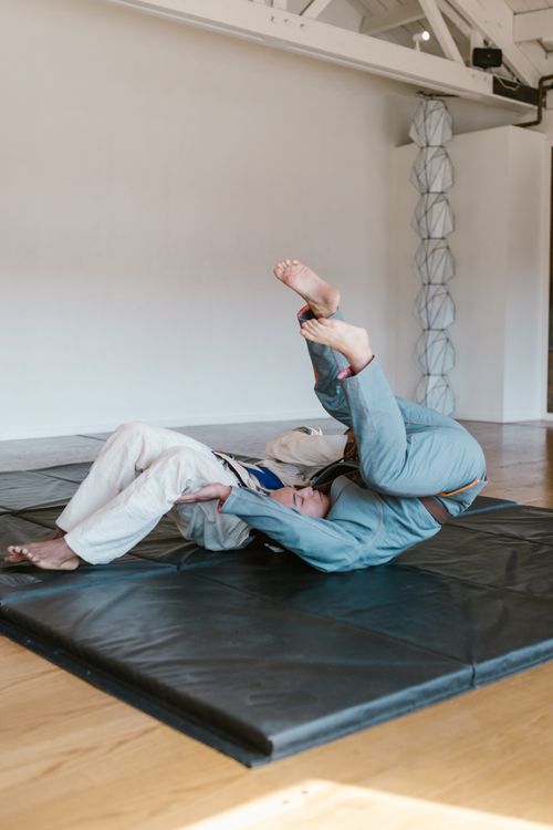 Free Two athletes in doboks practice a taekwondo wrestling technique on mats indoors. Stock Photo