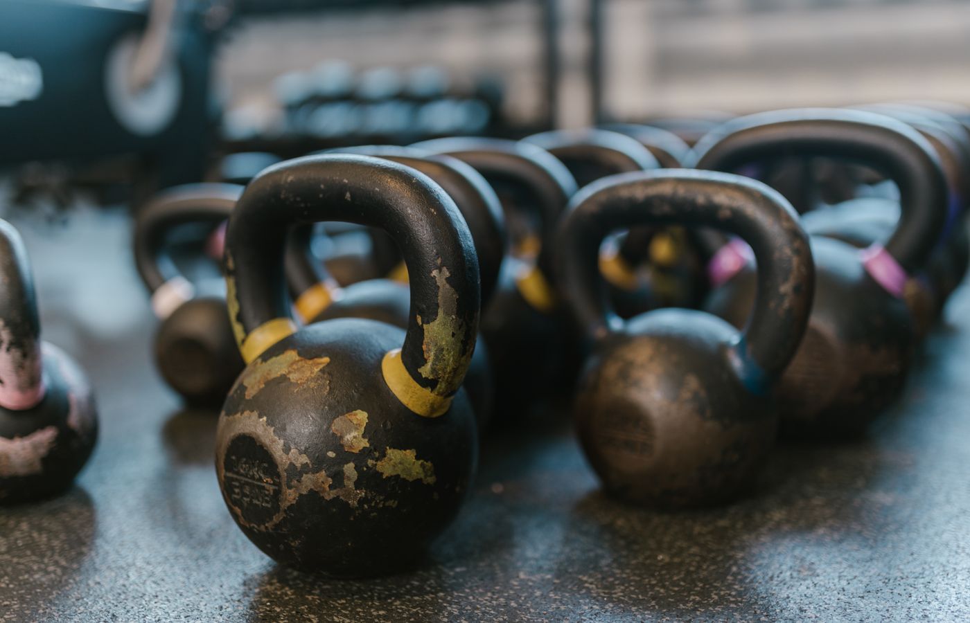 A collection of black kettlebells on a textured gym floor, perfect for fitness enthusiasts.