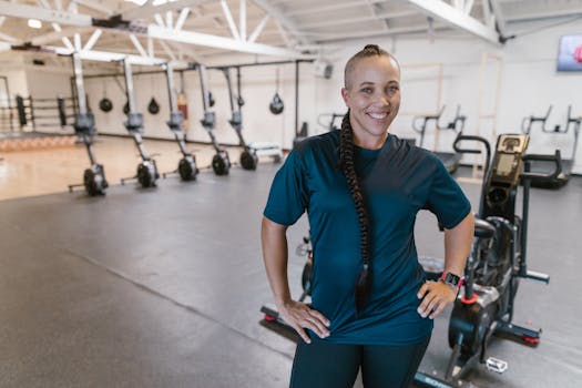 Smiling woman with braided hair standing confidently in a modern gym environment.